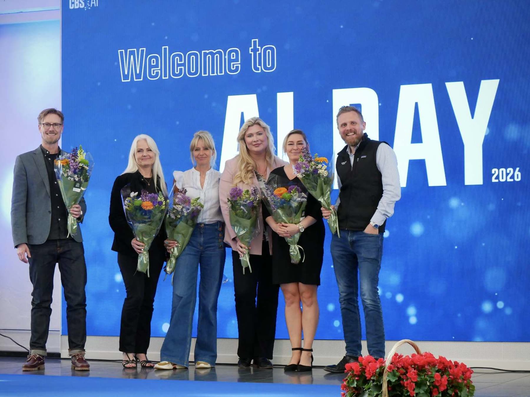 Speakers on stage with flowers at the close of CBS AI Day